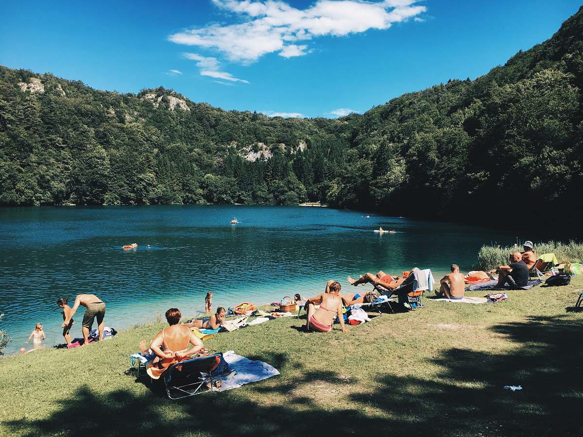 lake group of people gathering near lake under blue sky during daytime tree