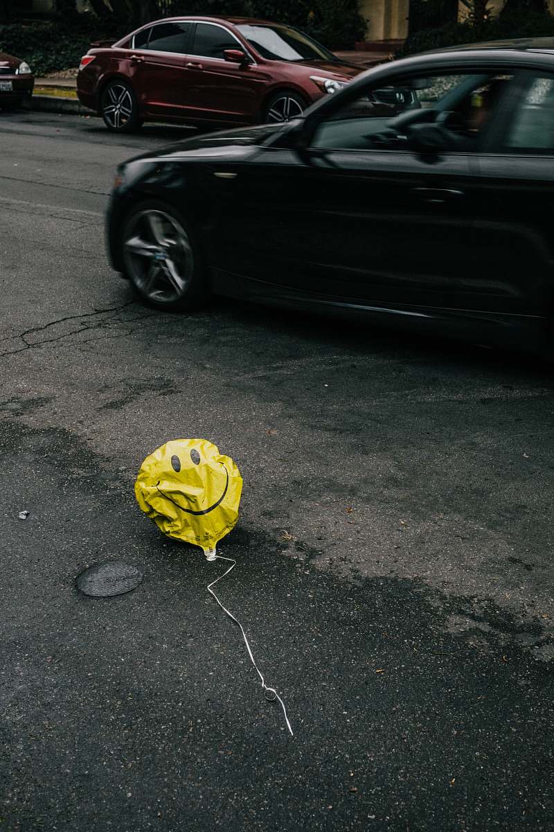 automobile smiling emoji balloon beside black car during daytime transportation