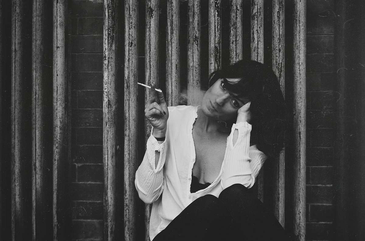 person grayscale photo of a woman holding a cigarette people