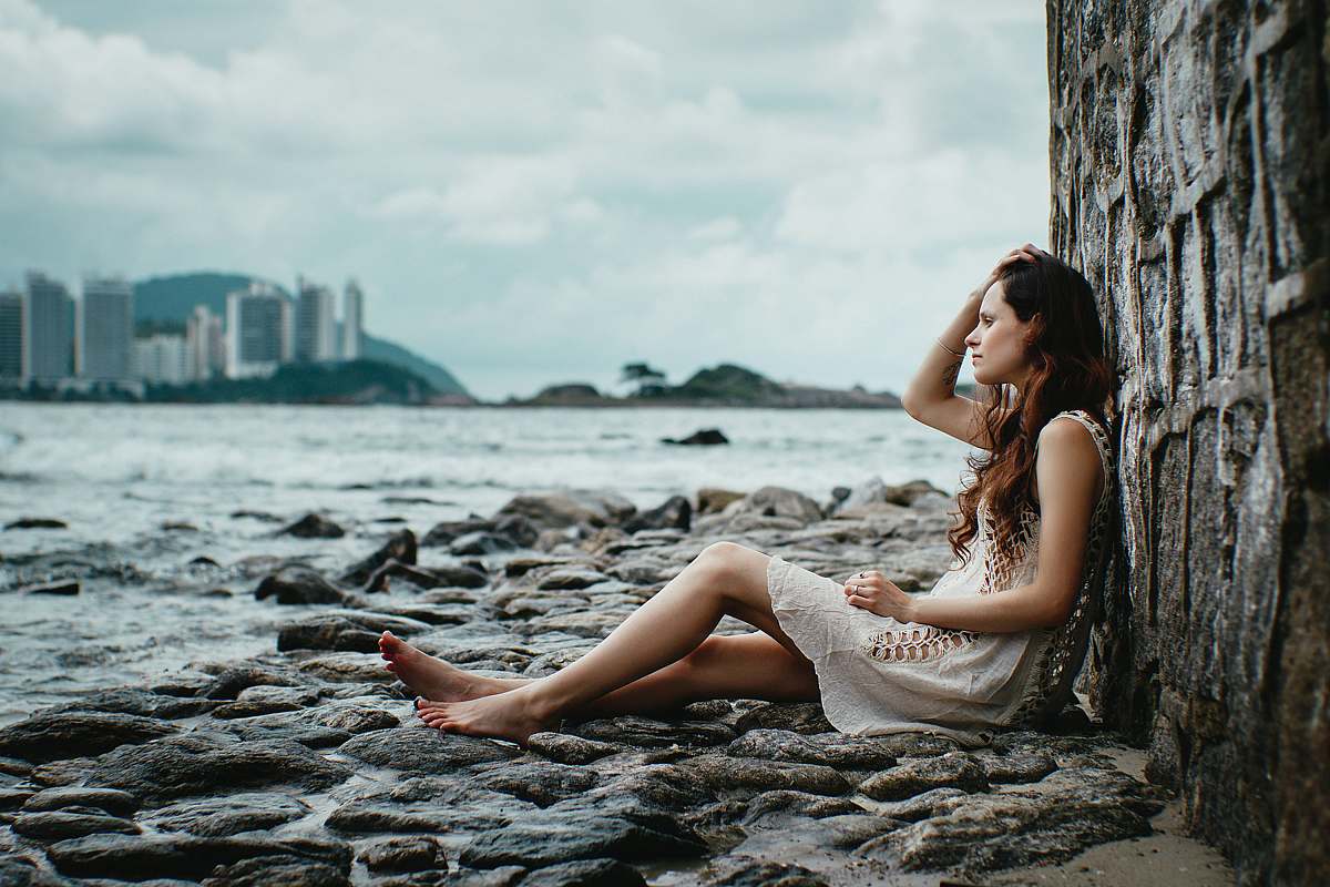 person woman leaning on stone wall near body of water human