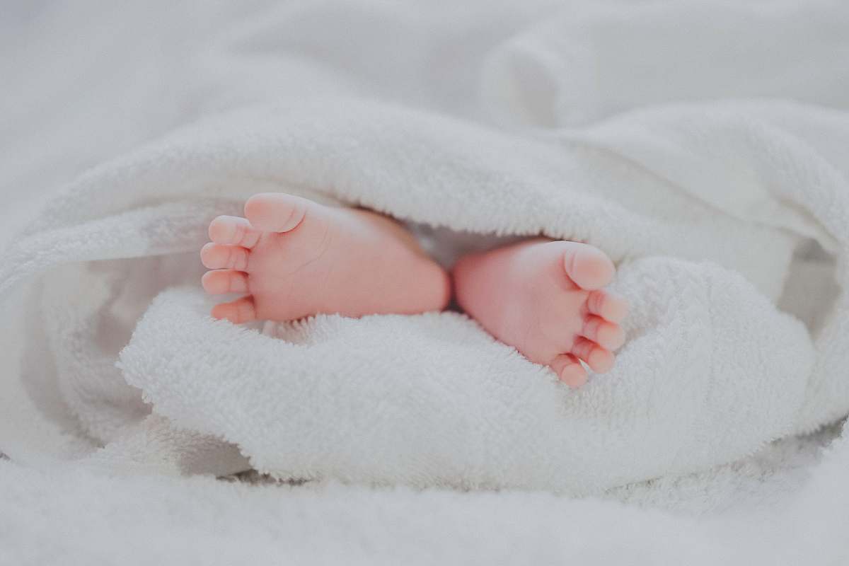 heel barefooted baby covering white blanket toe