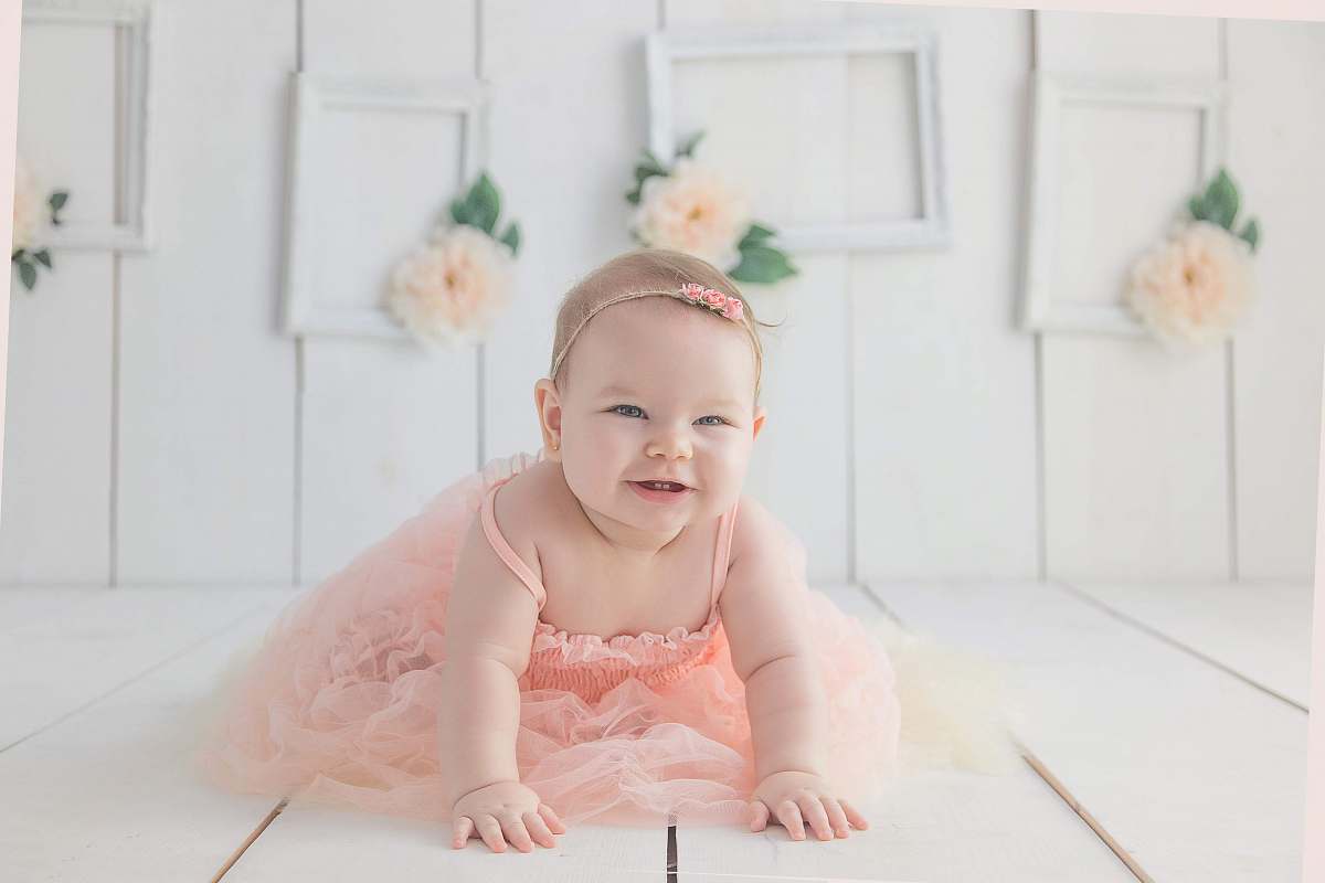 human girl crawling on white floor while smiling person