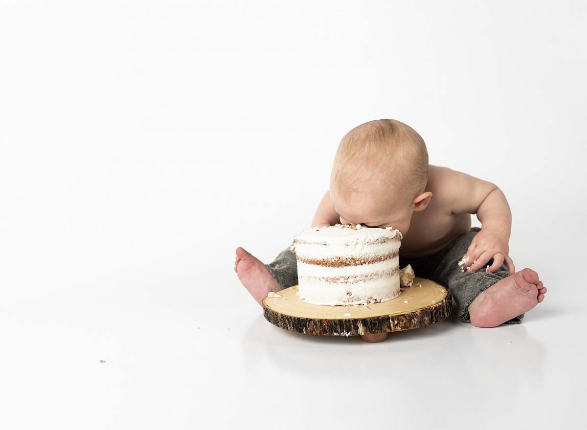 person kid sitting beside round cake close-up photography human
