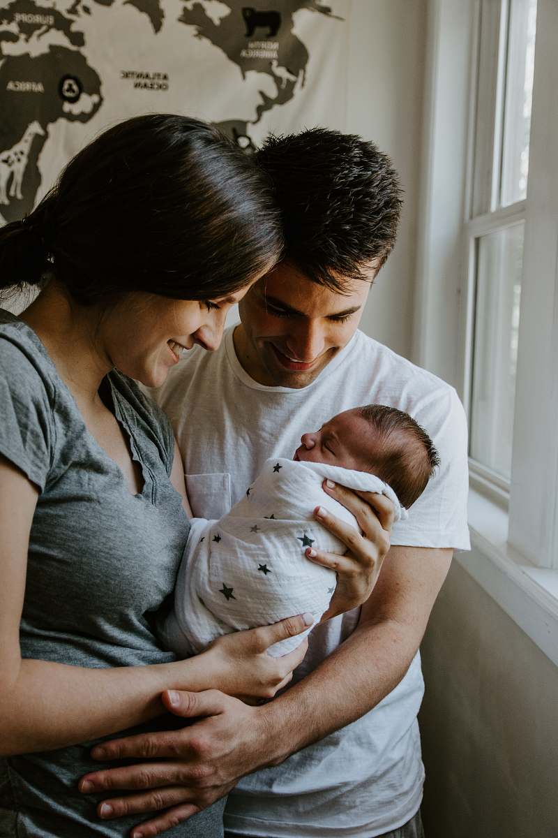 human woman holding baby beside man smiling newborn