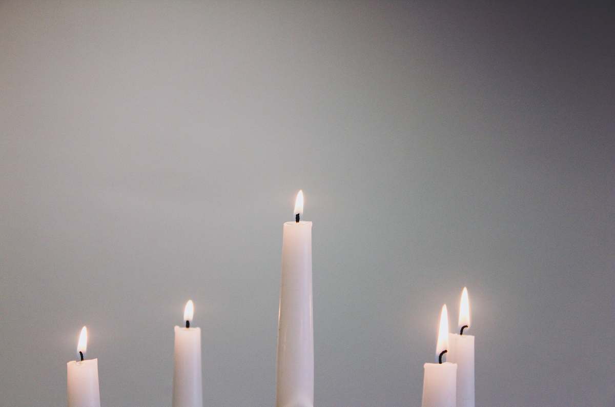 grey five lit white taper candles flame