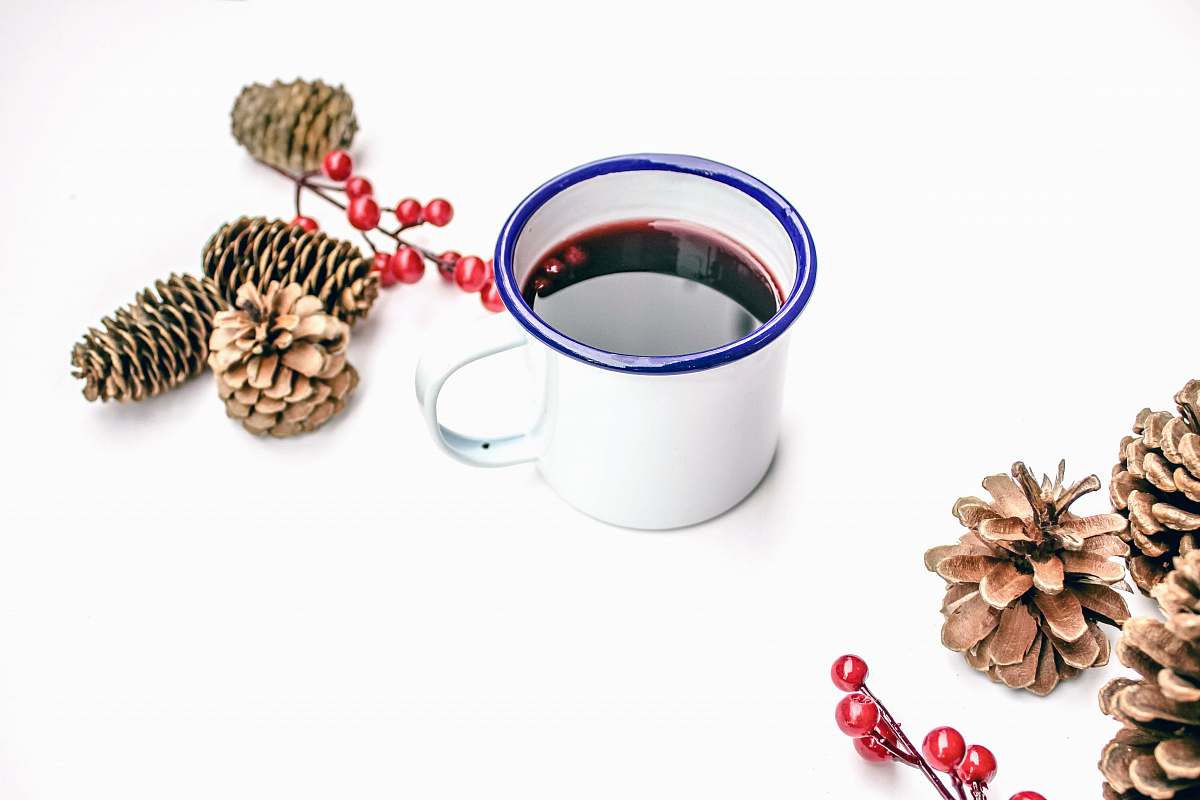 cup black liquid on white mug beside pine cones london
