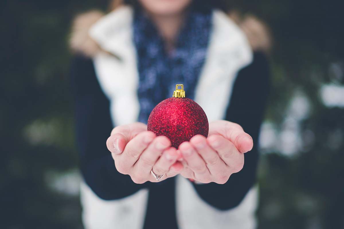 holiday shallow focus photography of person holding bauble holding
