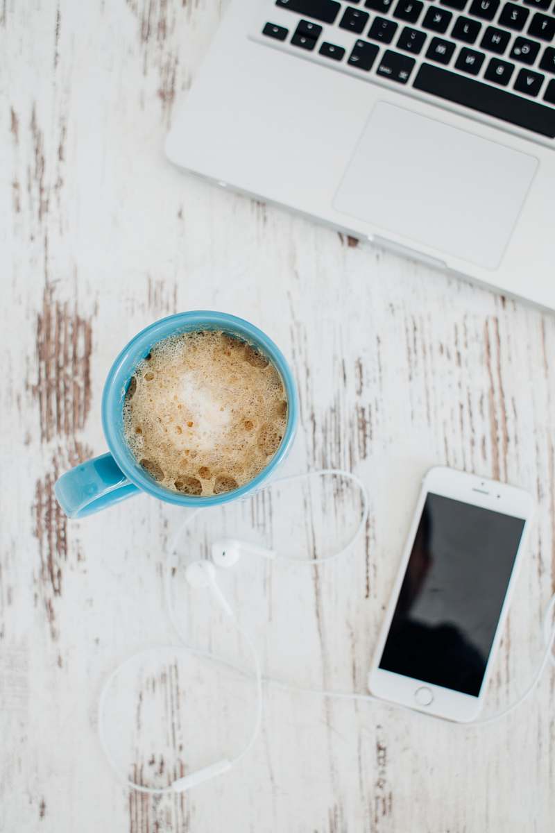 laptop flat lay photography of coffee in blue mug near Apple EarPods and gold iPhone 6 macbook