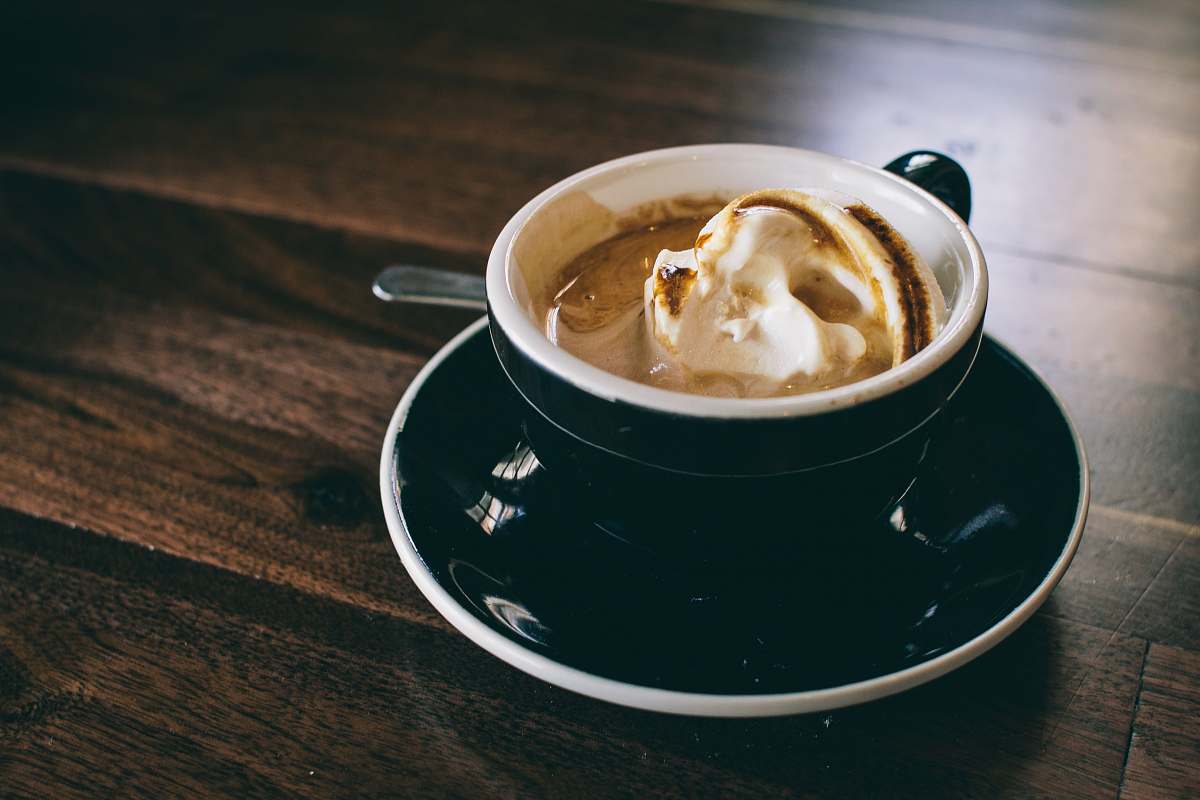 cup white and black ceramic mug filled with brown latte on round black ceramic saucer coffee cup