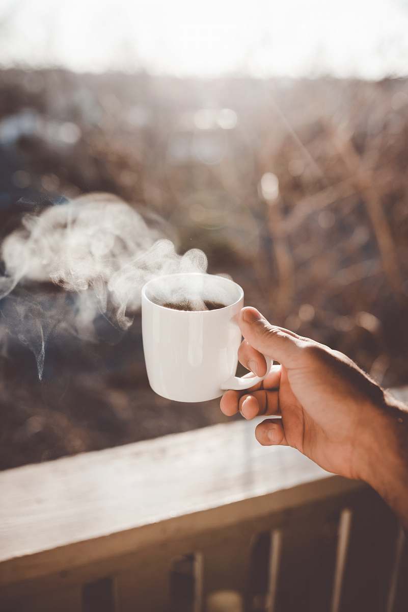 coffee person holding white ceramic cup with hot coffee tea