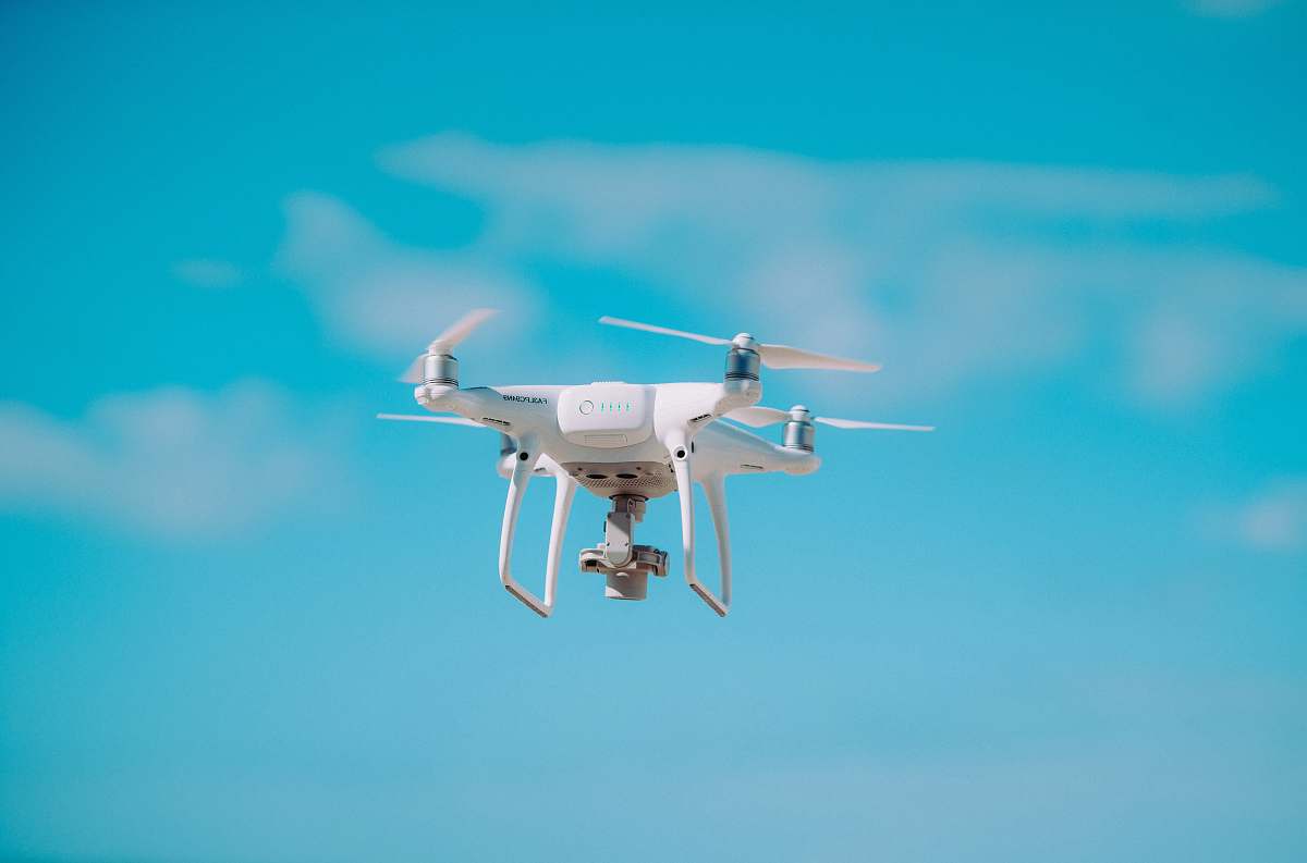 fly white quadcopter flying during daytime flight