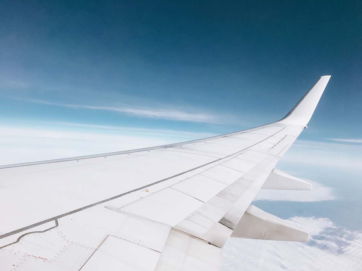 blue white airplane flying over white clouds plane