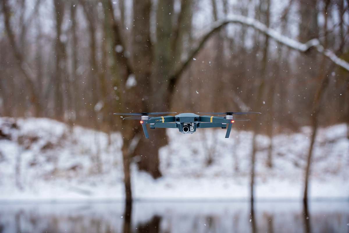 camera flying black drone during winter winter