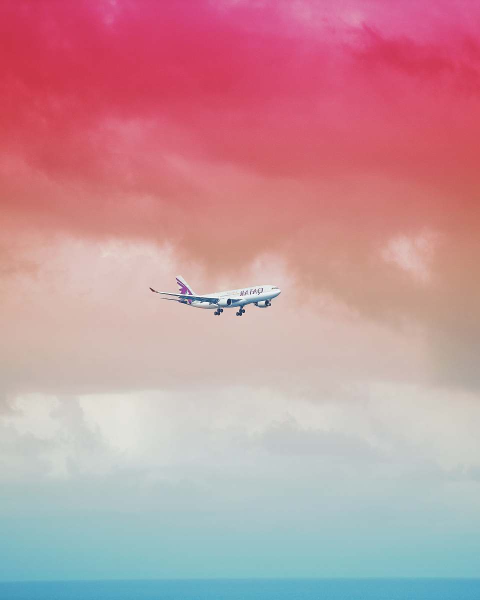 color Qatar Airlines airplane flying under red cloud formation maldives