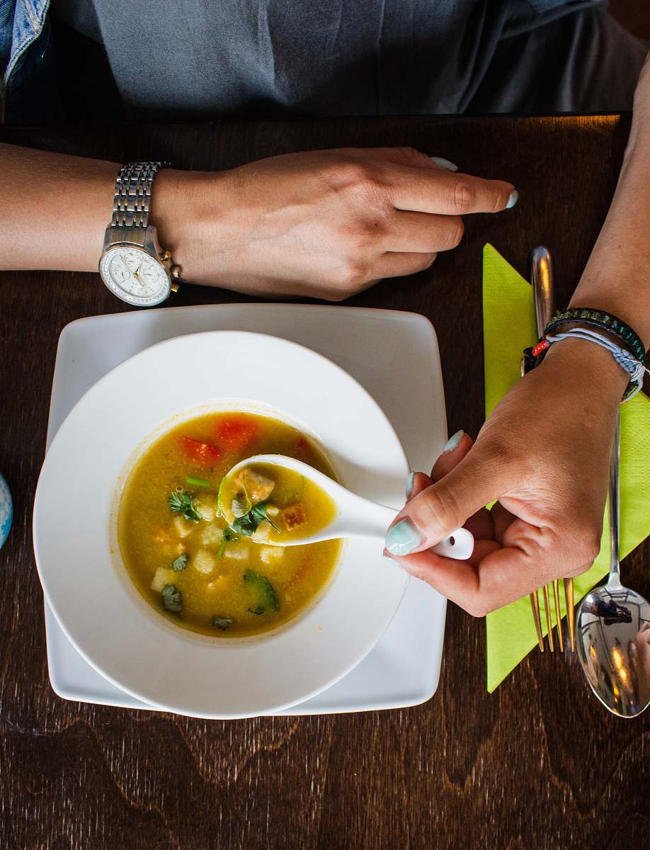 meal person holding spoon with soup on it bowl