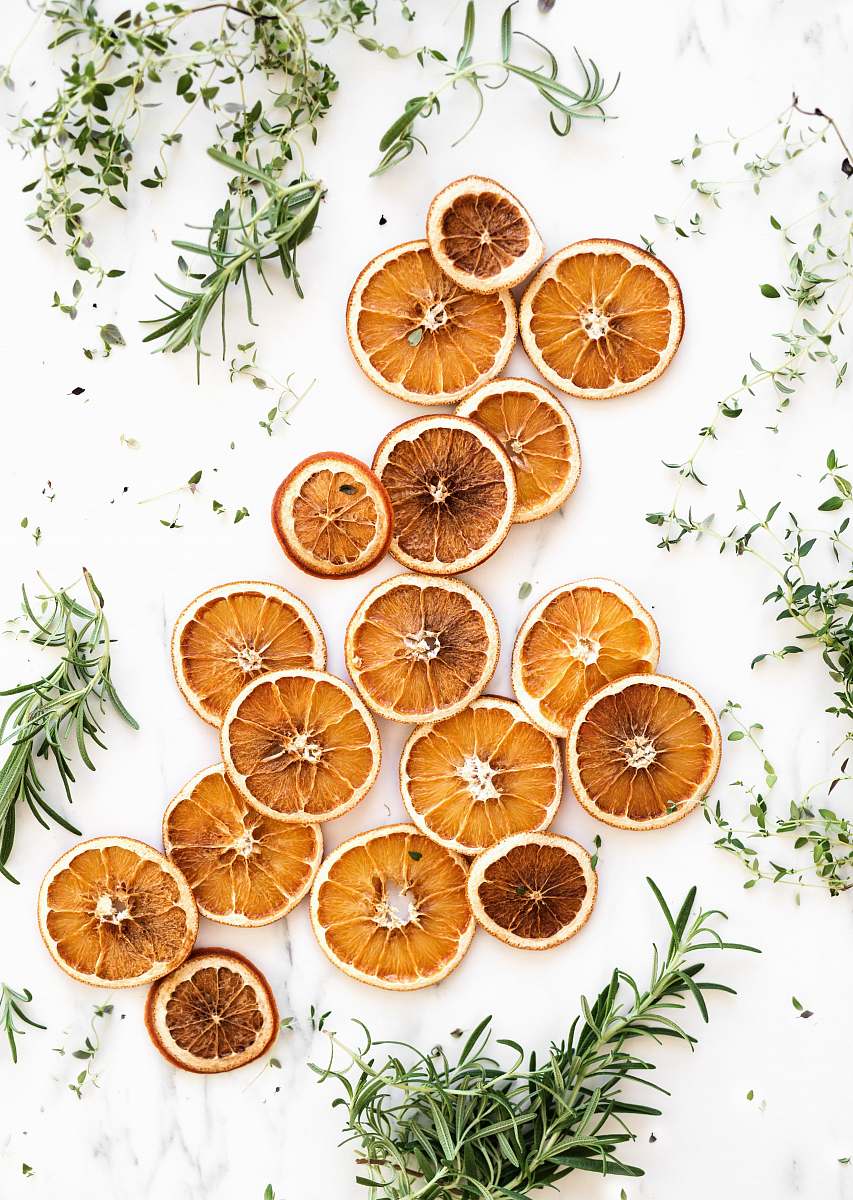 fruit sliced lemons surrounded by green herbs orange