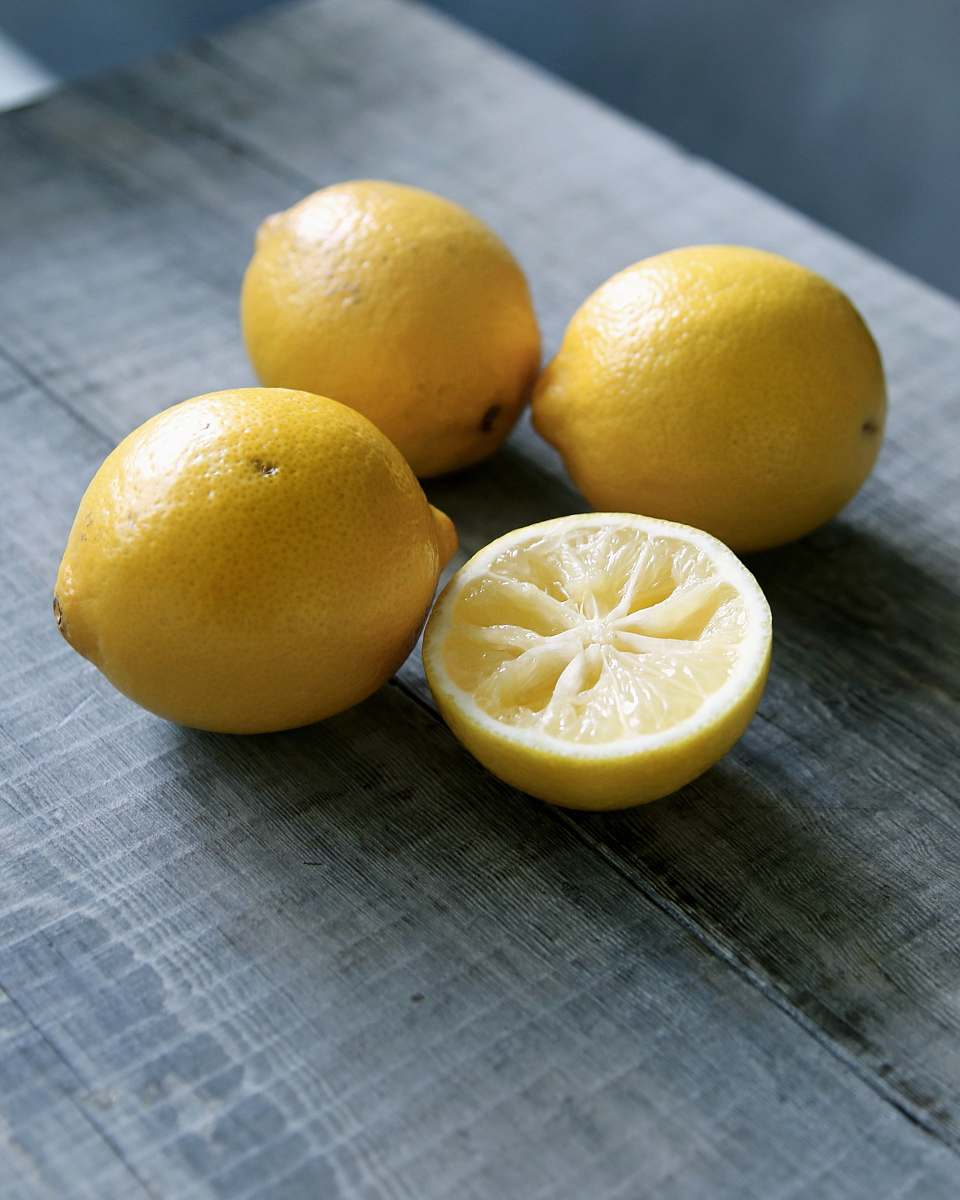 fruit three yellow lemons beside sliced lemon placed on gray wooden surface lemon