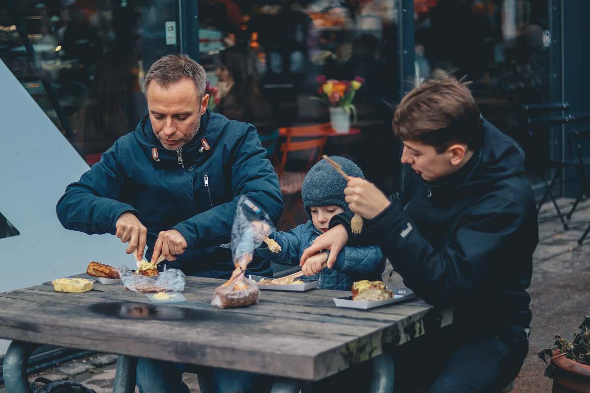 person two man and boy sitting in front of table eating human