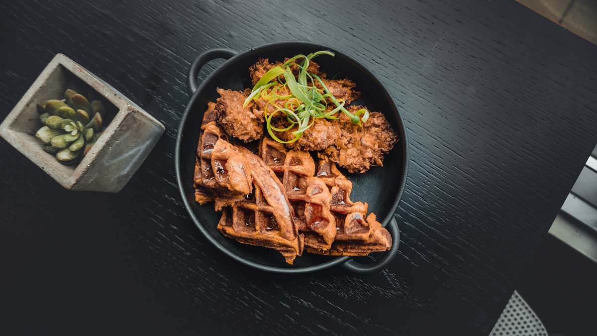 pasta waffle near fried food in black pot near green succulent plant noodle