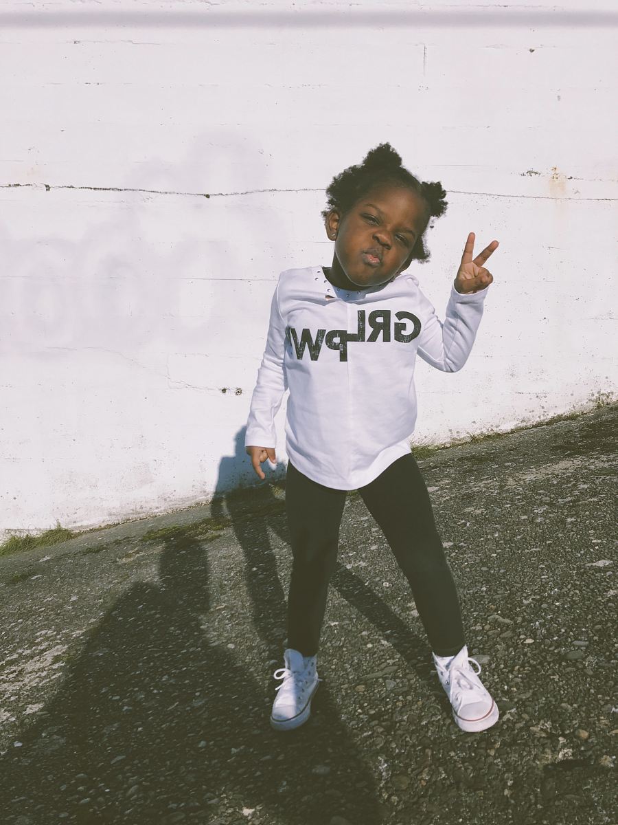 girl wearing white and black sweater doing peace hand sign