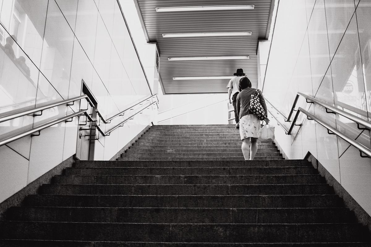 grayscale photography of woman walking on stair