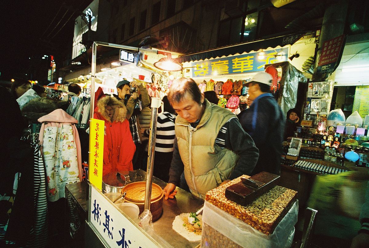 man preparing food on food stall with light bulb