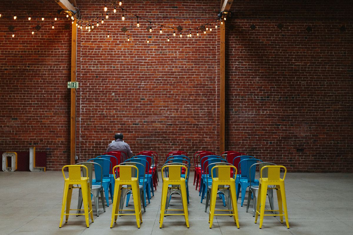 man sitting on red chair in front of brown concrete brick wall