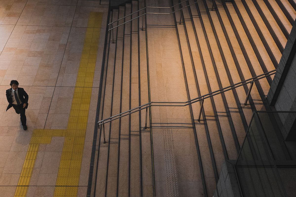 man walking in front of grey steel stair railing