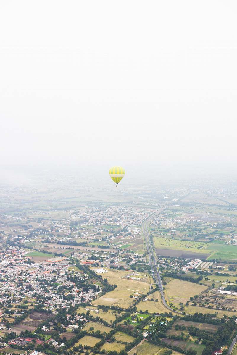 sky photo of yellow hot air balloon floating above houses hot air balloon