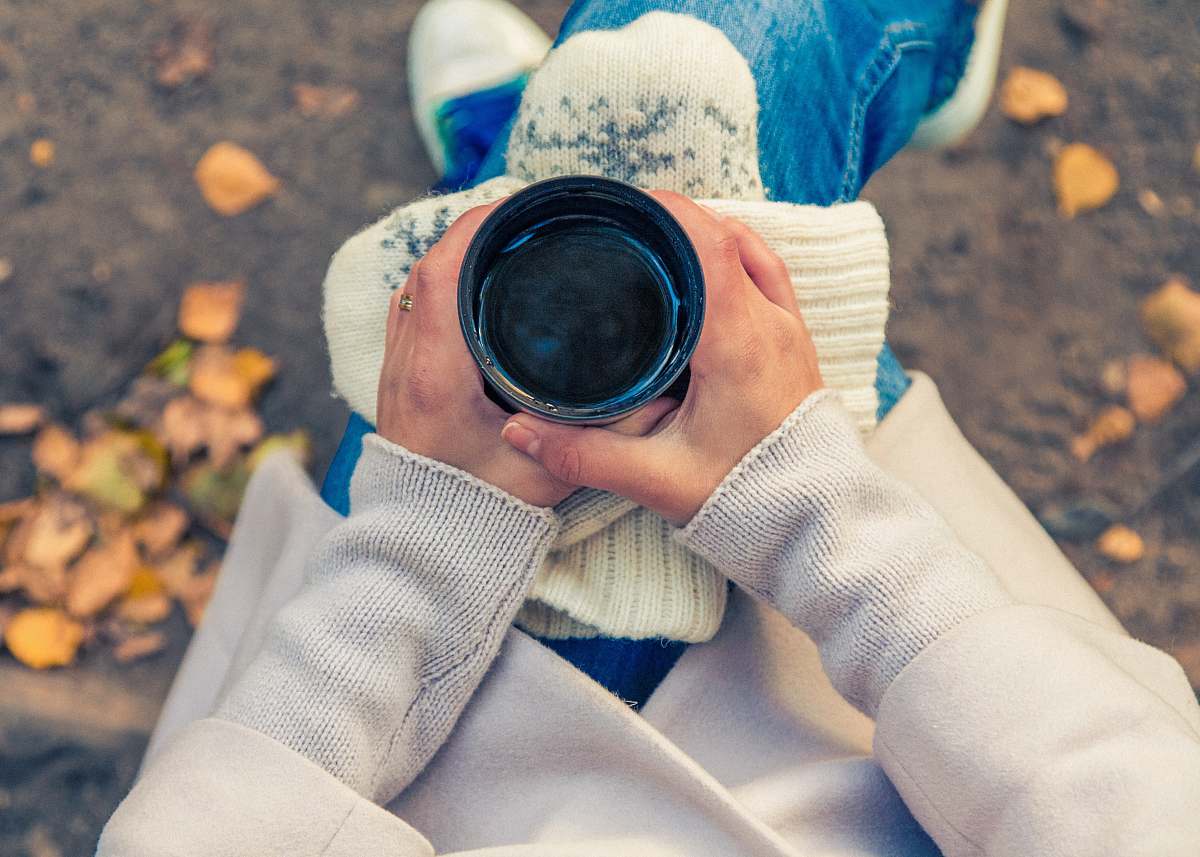 human person holding black cup on top of person's lap person