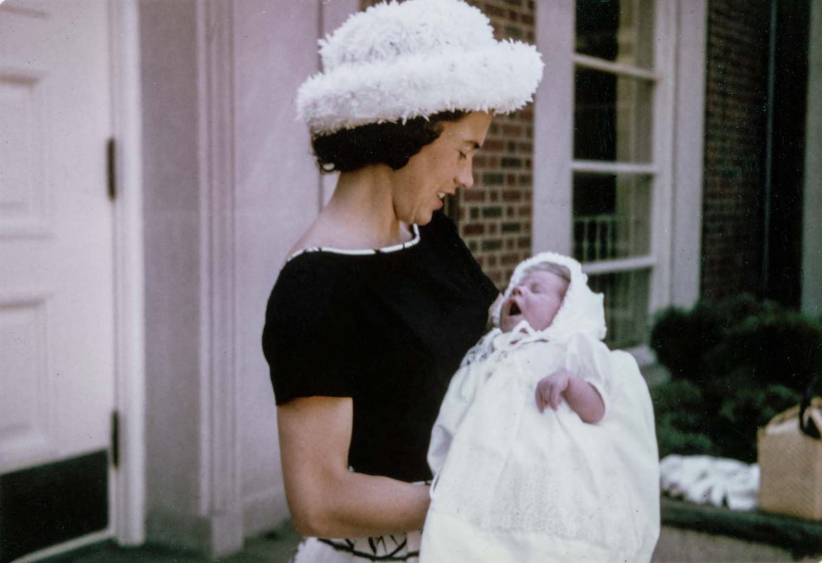 mother woman carrying baby standing near white wooden door baby