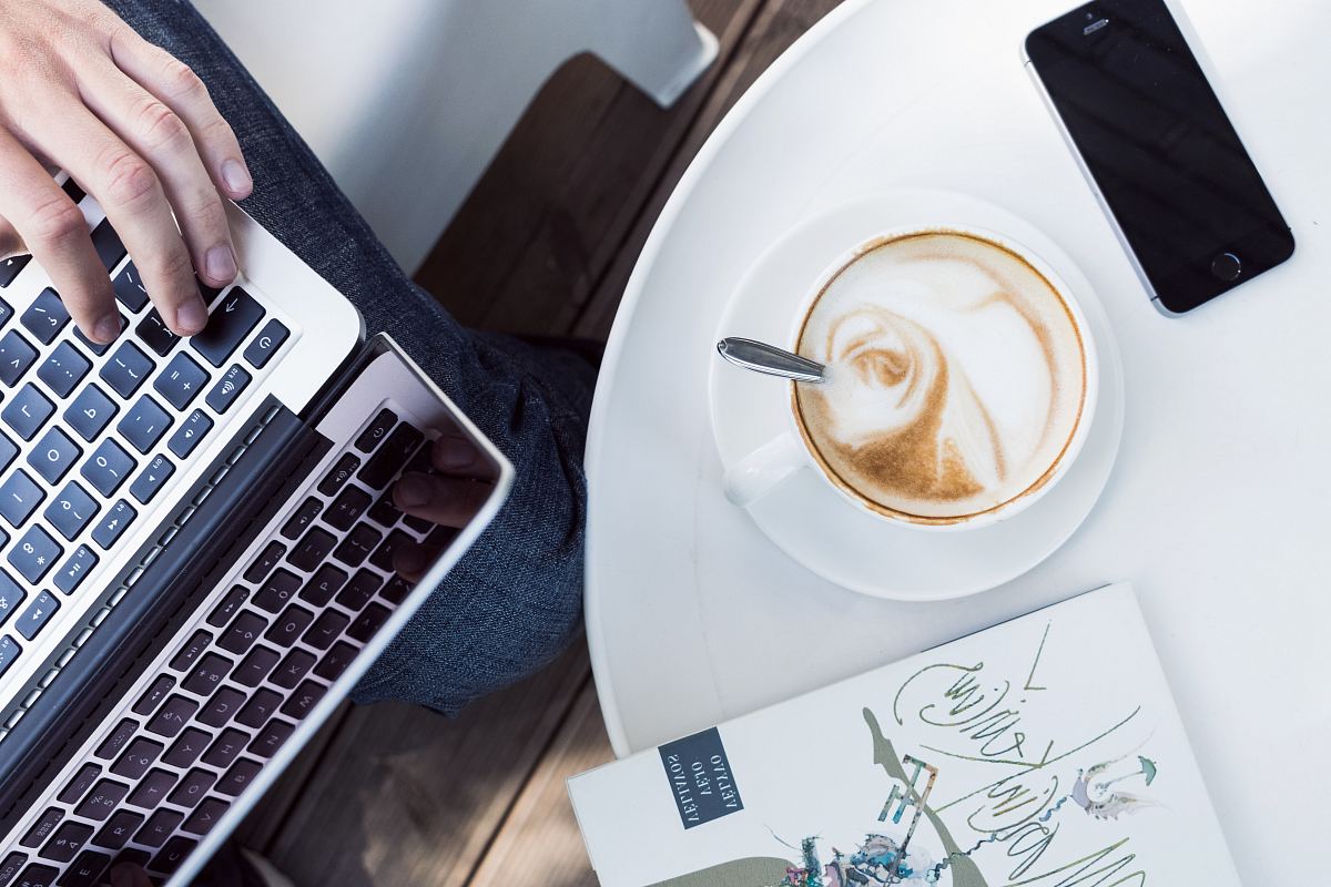 person using laptop near cup of coffee