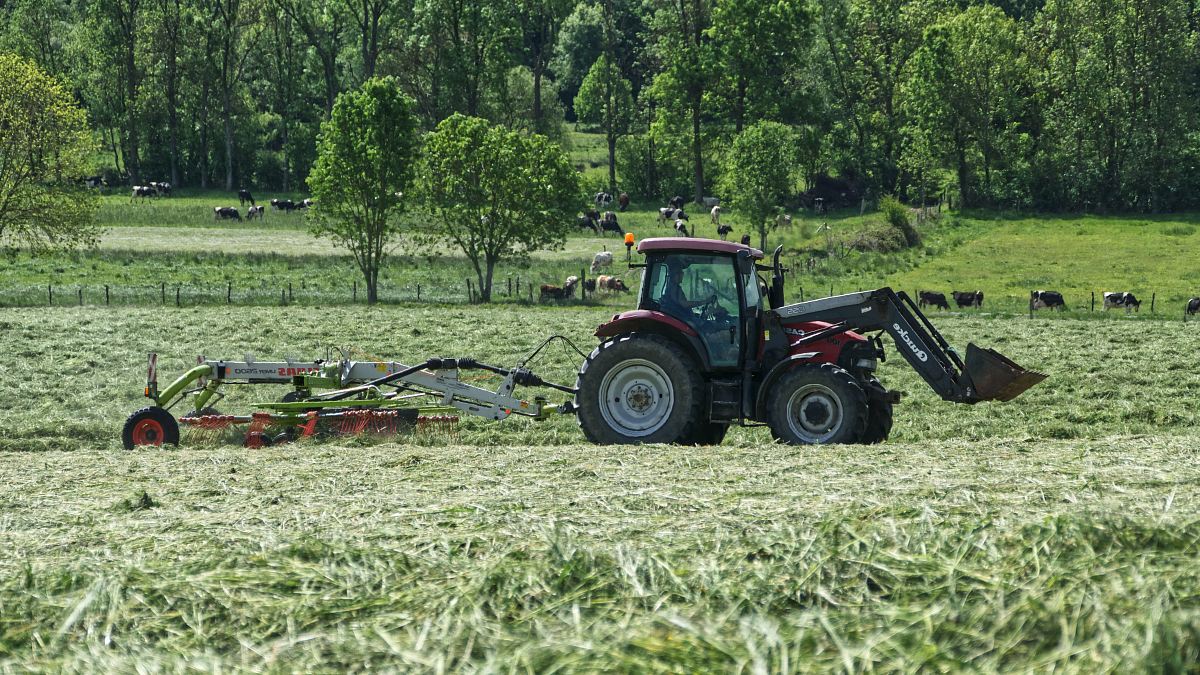 red tractor with farming attachment on field during daytime