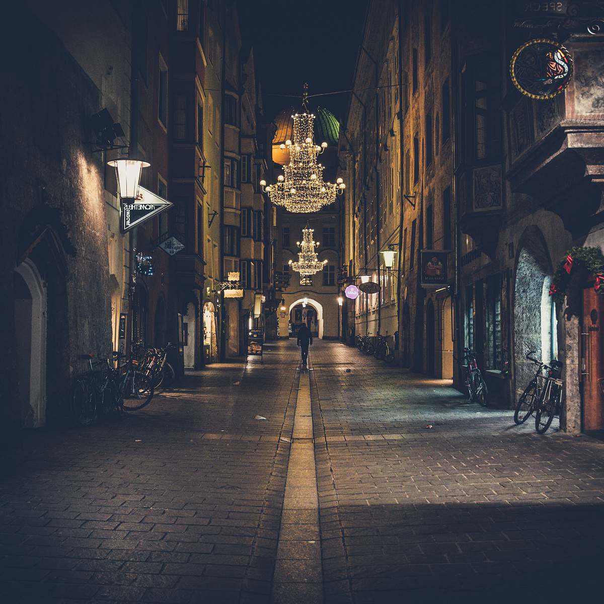 urban person walking on pathway showing lighted chandelier during night time city