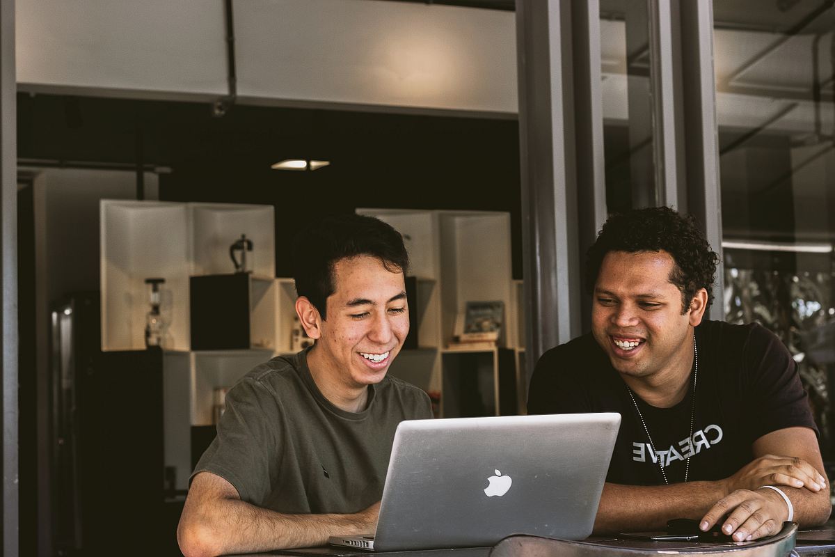 two smiling men looking at MacBook