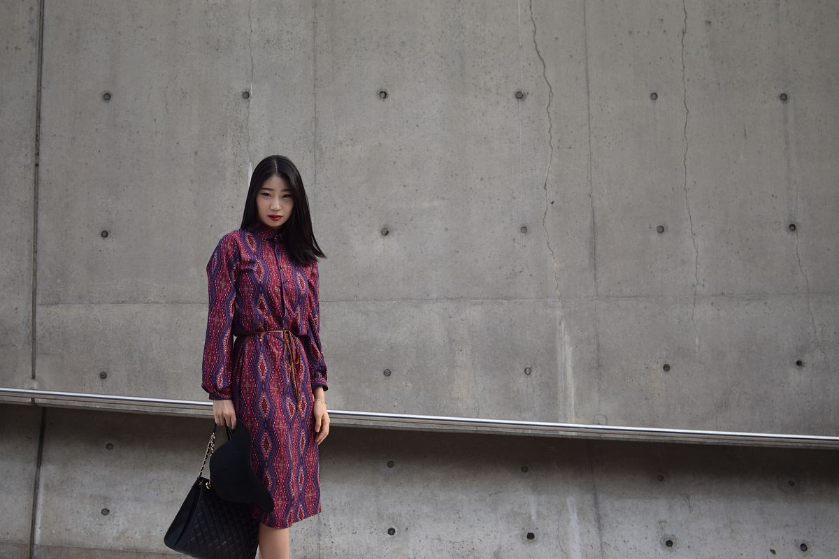 woman holding bag standing beside wall