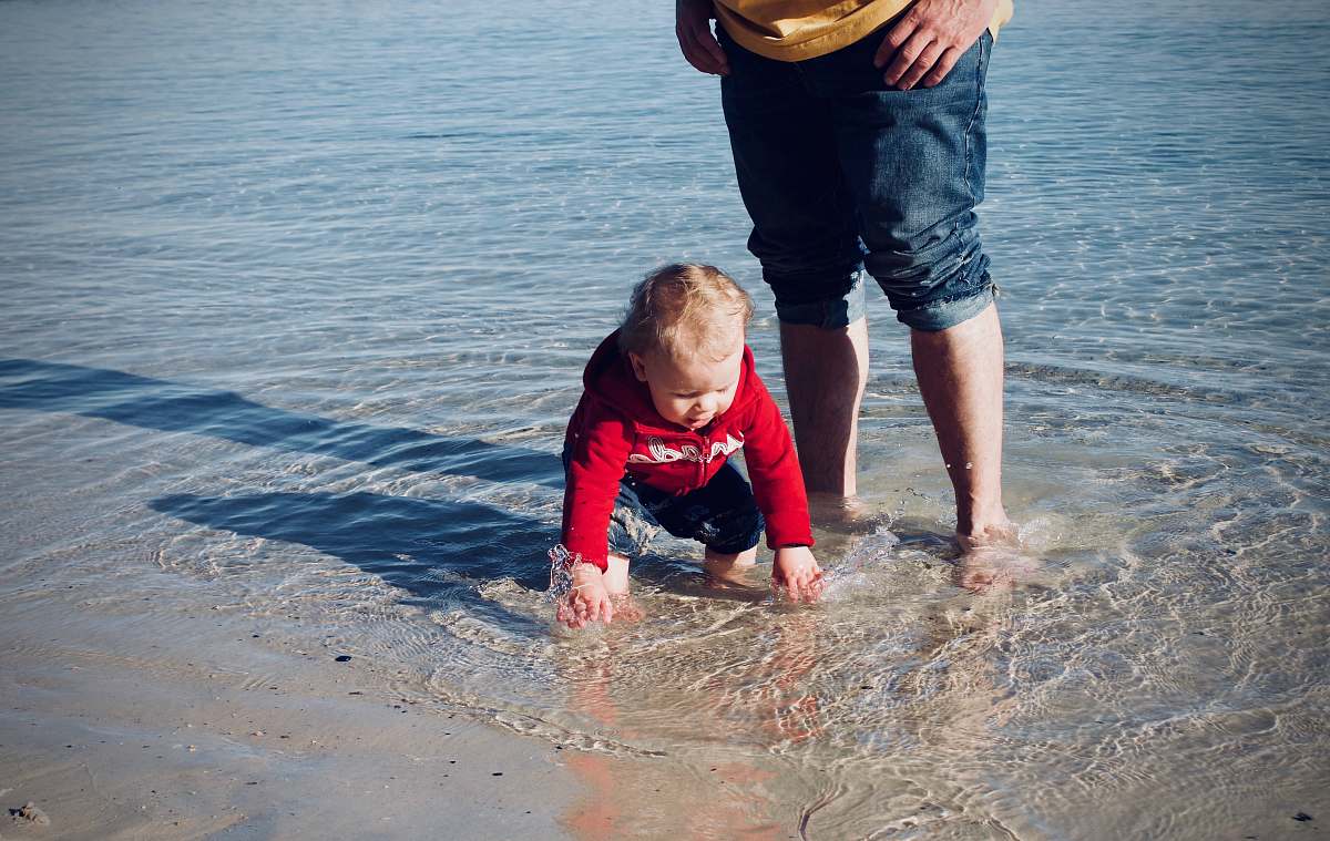 clothing baby standing on body of water pants