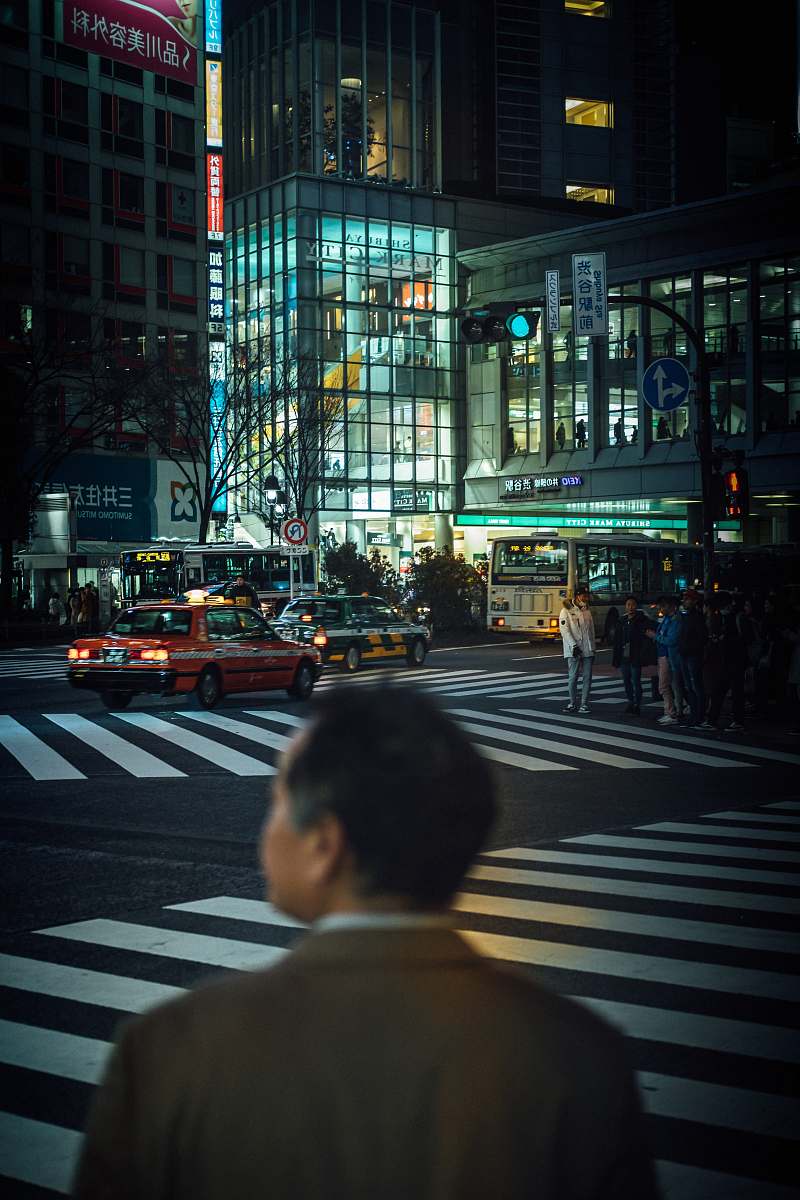 tarmac man standing near road beside buildings during night time road