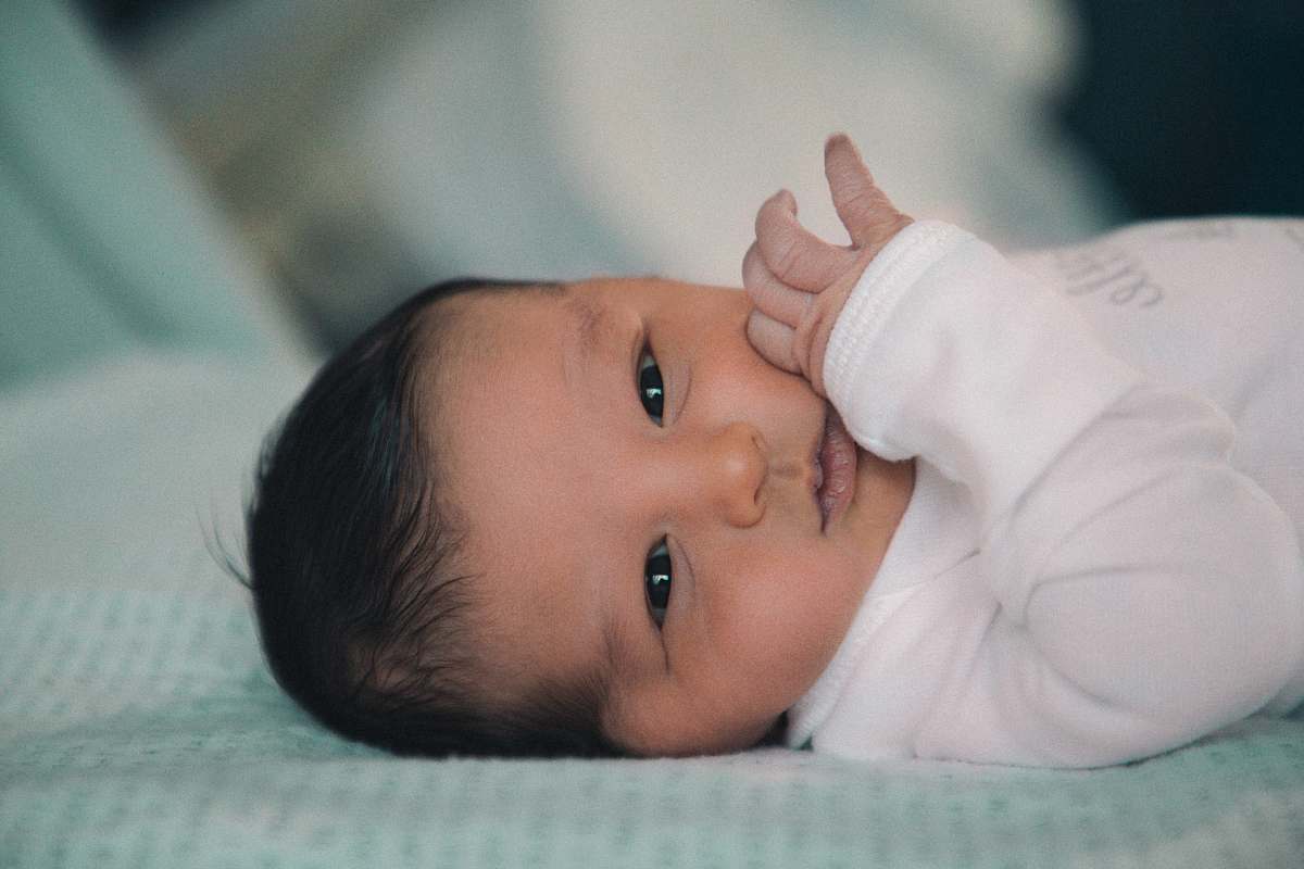 human baby in white shirt lying on bed person
