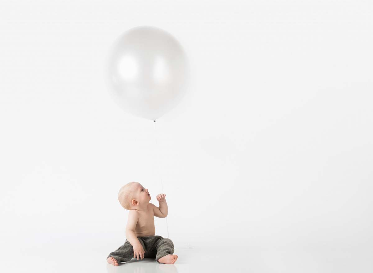 balloon boy sitting wearing black pants under white balloon ball