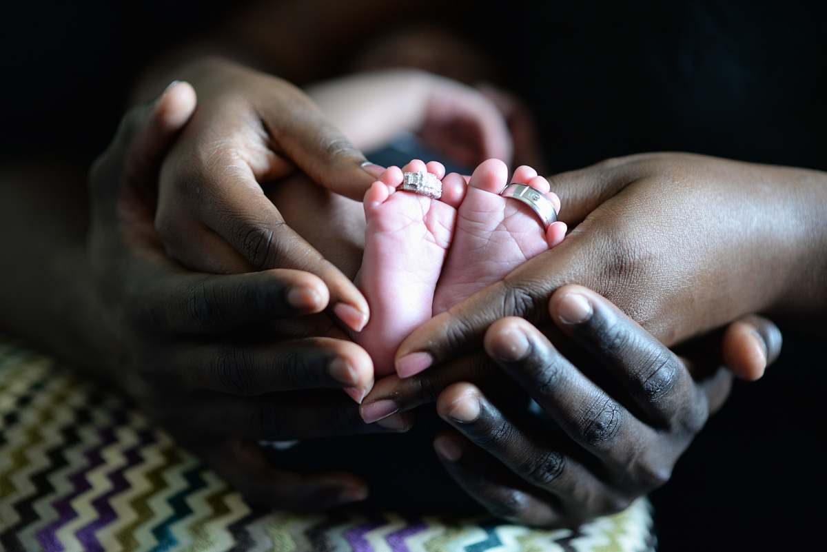 family person touching baby's feet with two silver-colored rings hand