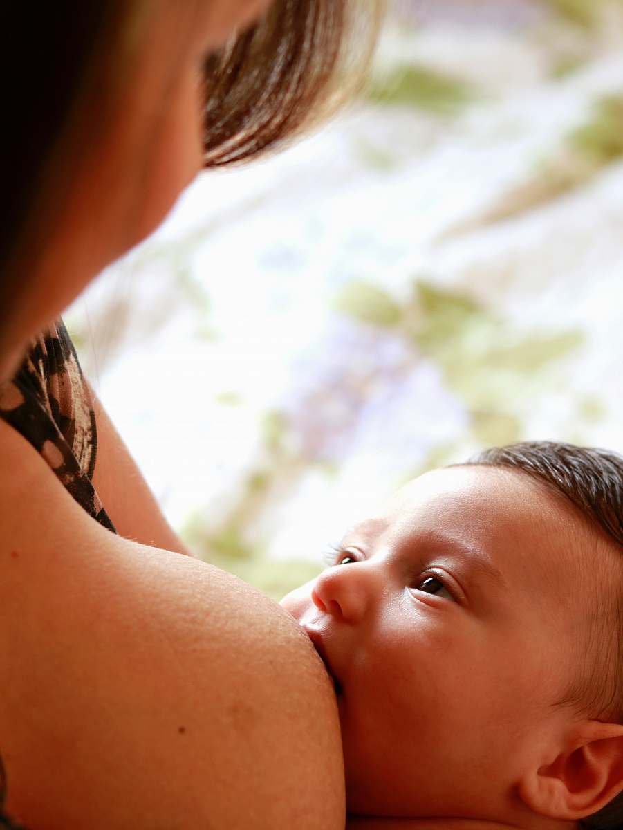 human woman breastfeeding baby during daytime newborn
