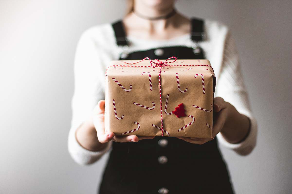 clothing tilt-shift lens photography of woman holding candy cane-print gift box in a well-lit room blouse
