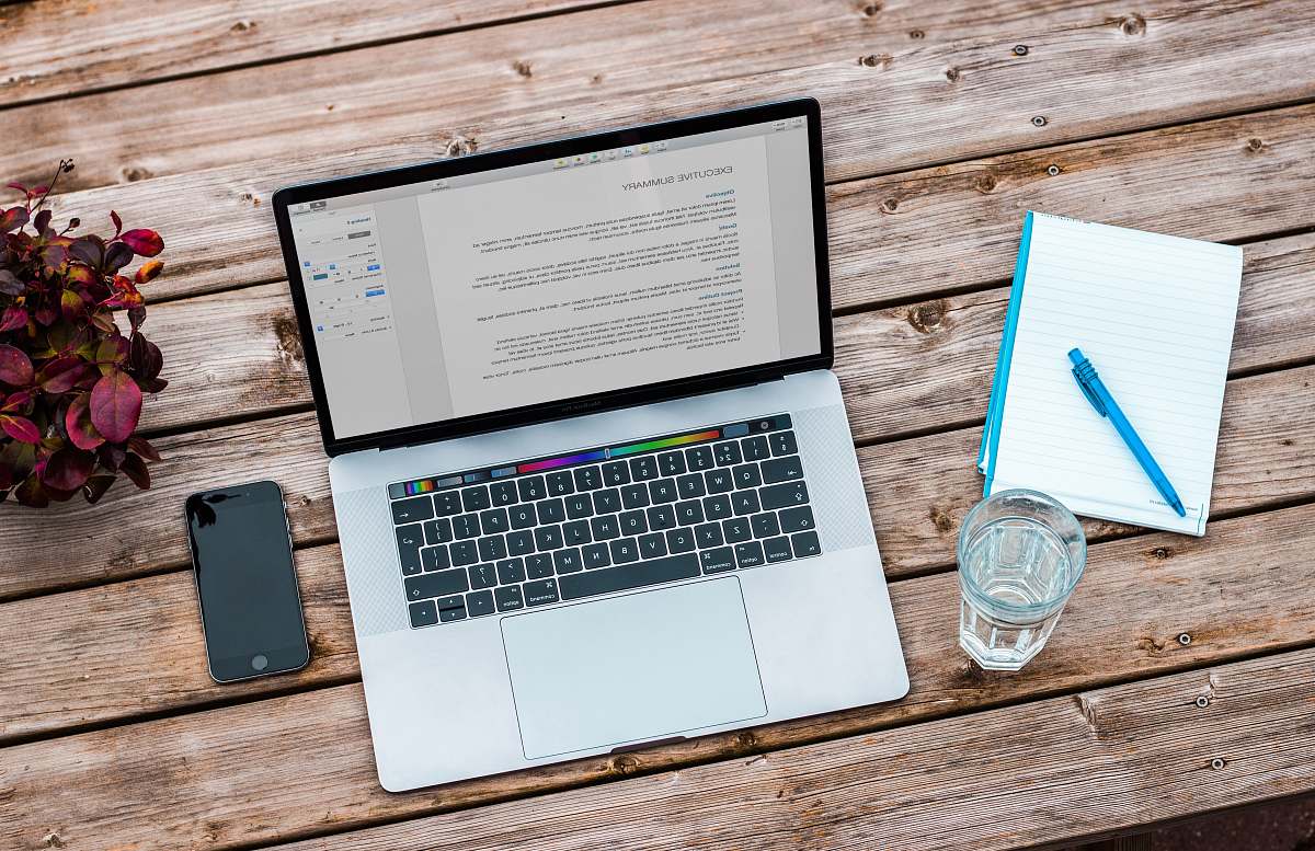 laptop silver MacBook beside space gray iPhone 6 and clear drinking glass on brown wooden top work