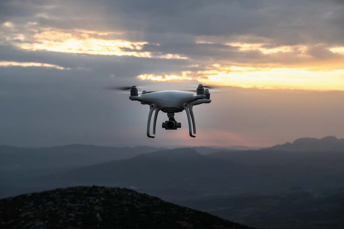 greece white DJI quadcopter drone flying in mid-air sunset