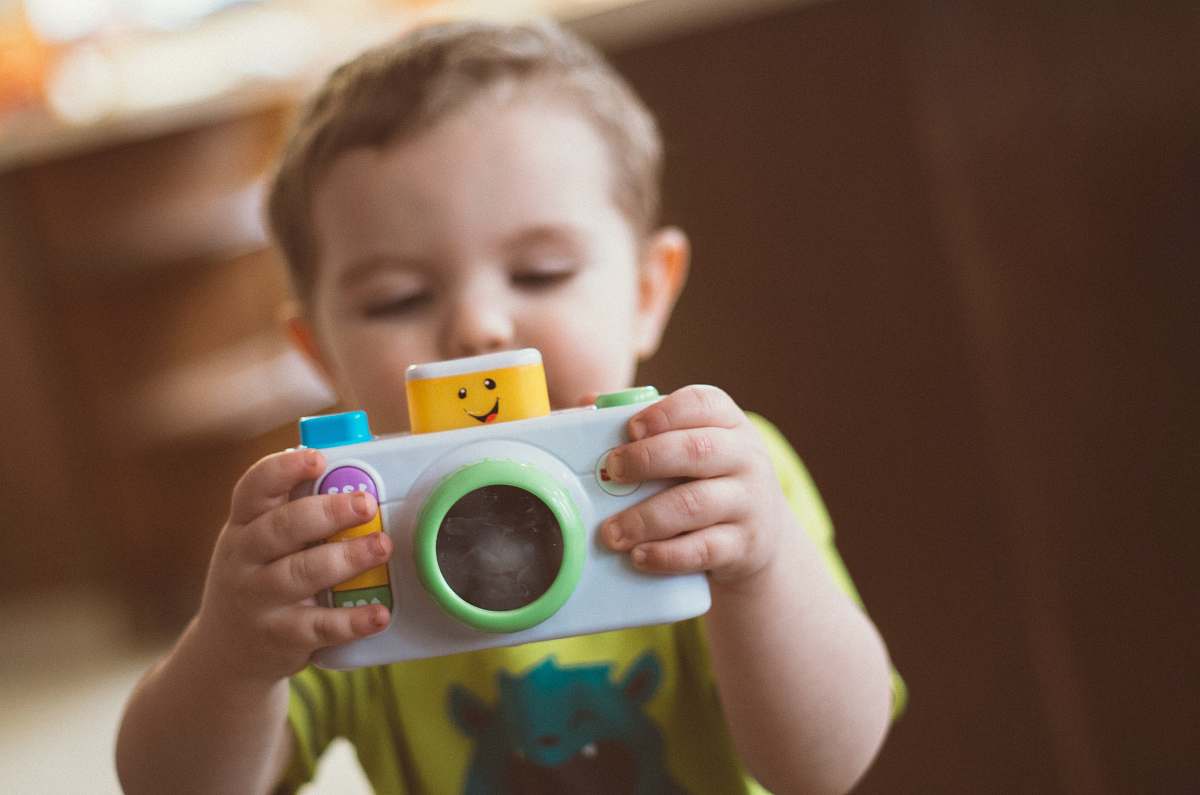 person toddler holding white camera toy people