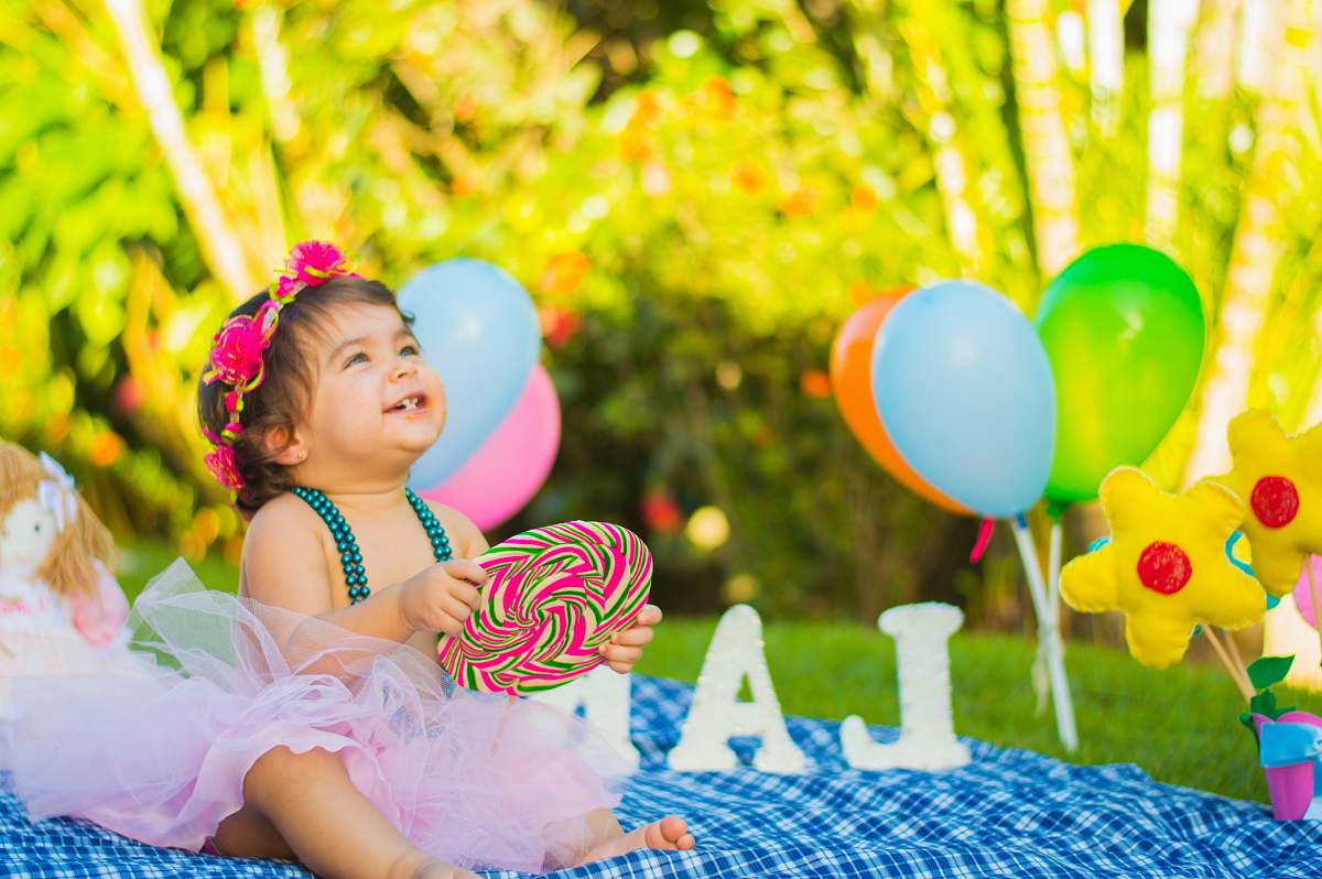 people toddler looking up while holding candycane in party balloon