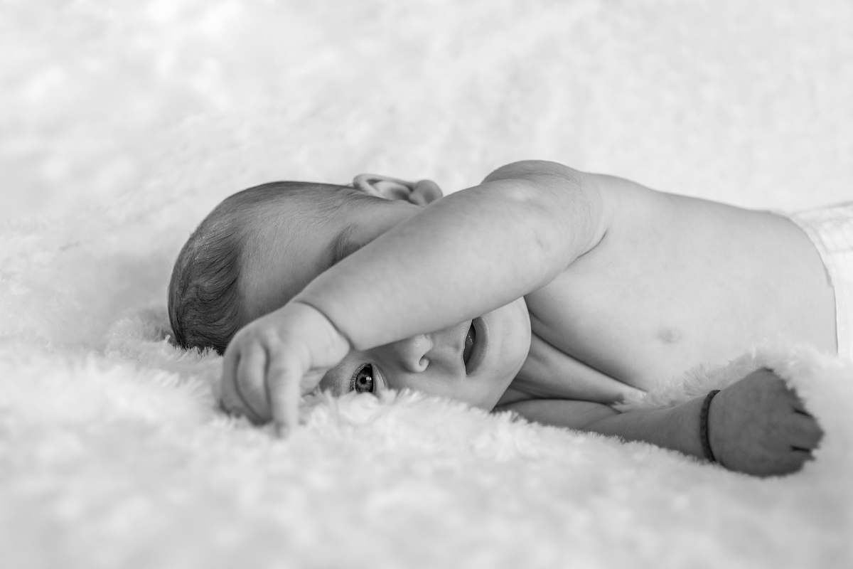 black-and-white topless baby lying on fleece grey