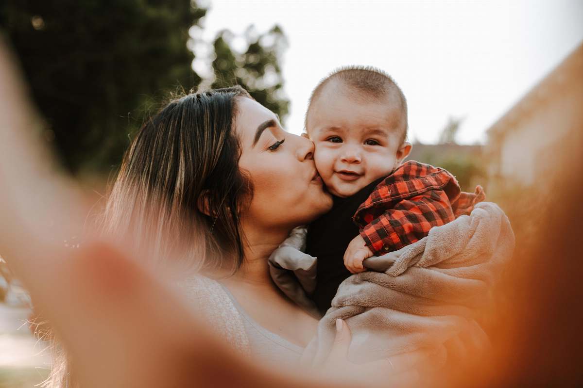 person woman kiss a baby while taking picture people