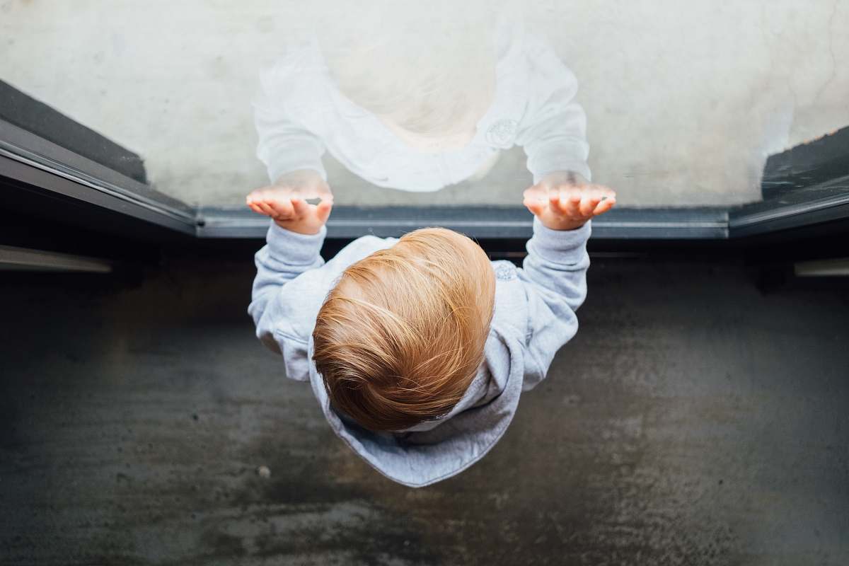 baby blonde haired boy in grey top leaning on glass door playa provisions